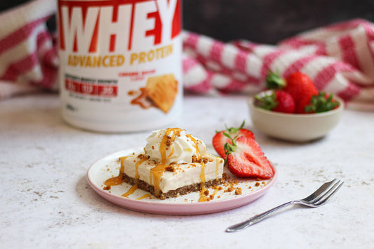 Caramel Biscuit Cheesecake on a plate in front of a tub of Caramel Biscuit Per4m Whey Protein.